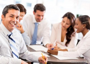 man-smiling-in-white-shirt-and-tie-near-other-workers-in-white